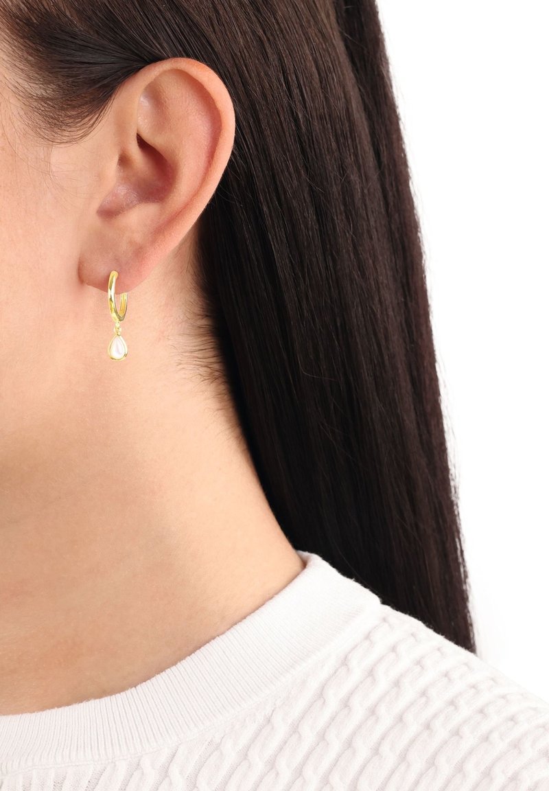 Goldene Ohrstecker mit einem tropfenförmigen Edelstein, der von der Basis hängt. Schlichte Gestaltung, polierte Oberfläche und leichtes Aussehen.