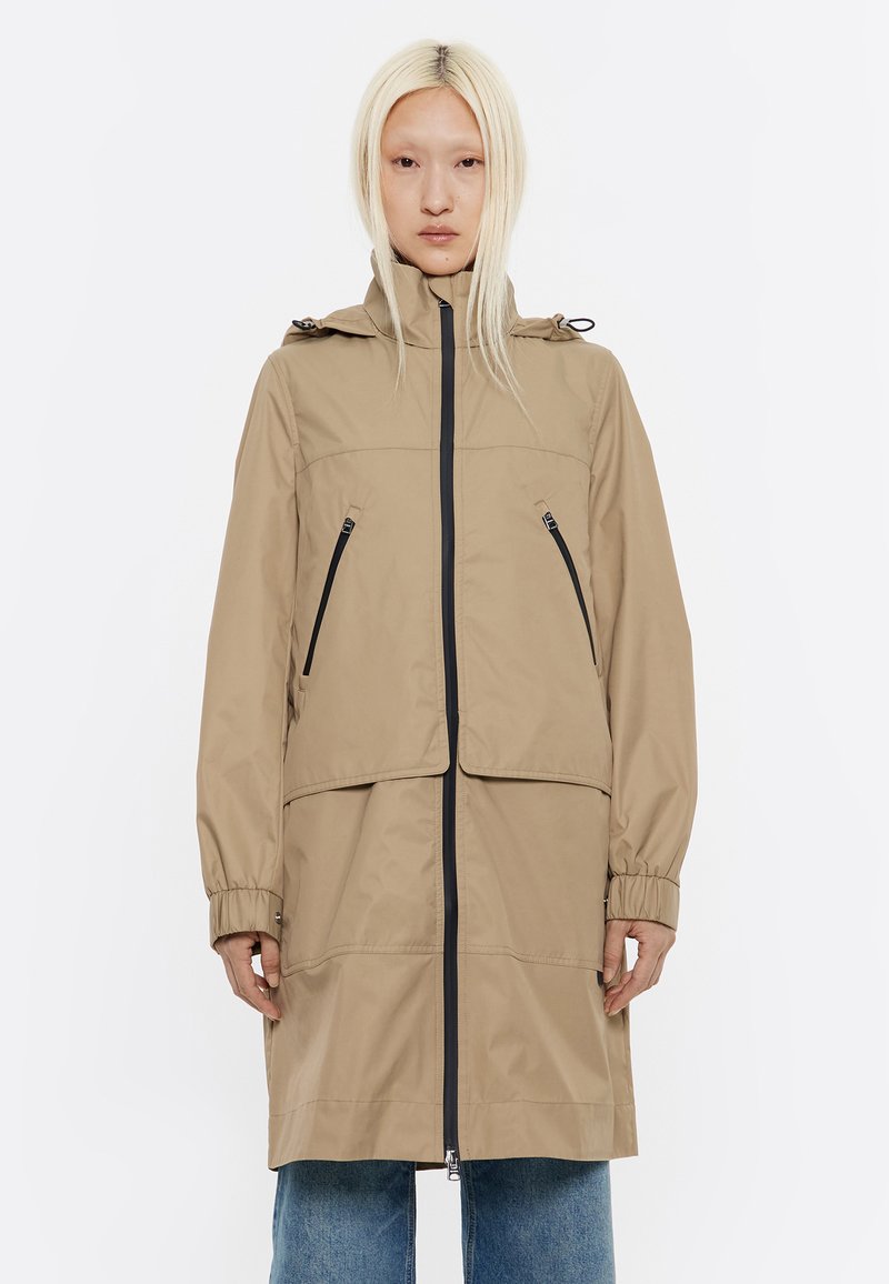 Beige wasserfeste Jacke mit Kapuze, Reißverschluss vorne, zwei Brusttaschen und elastischen Bündchen. Glatte Oberfläche und lockere Passform.