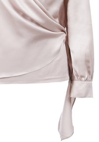 Helle rosa Seidenbluse mit gewickeltem Design, langen Ärmeln mit gerafften Manschetten und seitlichem Bindedetail für einen eleganten Auftritt.