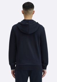 Granatowa bluza z kapturem o luźnym kroju, wyposażona w kaptur ze ściągaczem, ściągacze na rękawach i na dole, wykonana z miękkiego materiału o gładkiej fakturze.