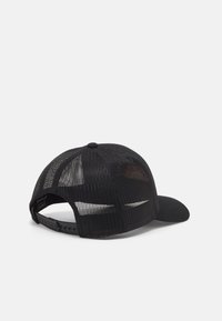 Melnā cepure ar stingru priekšpusi, acs aizmuguri un izliektu malu. Uzsverta ar pogu augšpusē un regulējamu sprādzi aizmugurē.