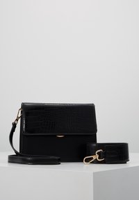 Borsa nera con fronte in stampa coccodrillo, corpo liscio, chiusura magnetica, tracolla staccabile, hardware in tonalità oro, forma rettangolare.