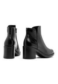 Czarne skórzane botki za kostkę z okrągłym noskiem i blokowym obcasem. Posiadają boczny zamek błyskawiczny, gładką teksturę oraz minimalne detale przeszyć.