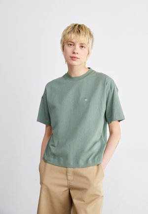 T-shirt à manches courtes, col rond en coton vert clair, avec un petit logo sur la poitrine gauche et une coupe droite.
