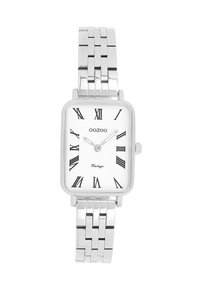 Montre rectangulaire argentée avec un bracelet en acier inoxydable, cadran blanc, chiffres romains noirs et une petite couronne sur le côté droit.