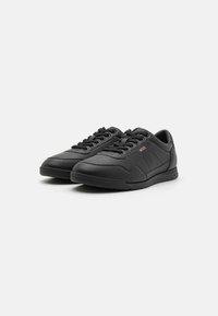 Black leather shoes with a smooth finish, rounded toe, and textured accents. Features flat laces, a cushioned sole, and brand logo.
