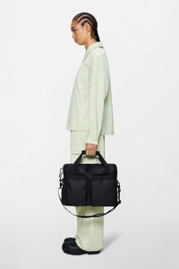 Svart nylonveske med doble frontlommer, håndtak på toppen og avtakbar skulderrem, vist mot en enkel hvit bakgrunn.