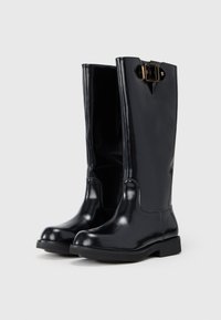 Botas negras brillantes hasta la rodilla con punta cuadrada, textura suave y un acento de hebilla dorada en la parte frontal superior, con una suela negra resistente.