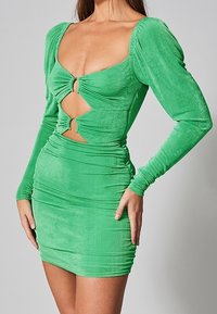 Robe mini verte à manches longues en tissu doux et extensible, dotée d'un décolleté plongeant et d'une découpe en forme de clé, avec des détails froncés le long du corps.