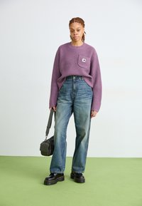 Suéter morado con relieve y bolsillo frontal, jeans de mezclilla azul de cintura alta y botas de plataforma negras. Bolso gris con strap.