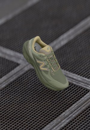 Sapatilha de corrida verde com parte superior em malha respirável, colo almofadado e detalhes em amarelo claro. Apresenta sola texturizada e detalhes reflexivos.