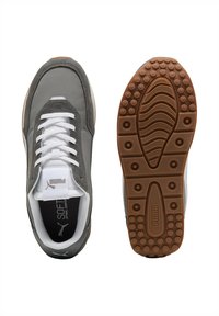 Zapatillas grises con una parte superior de suave ante y textil, cordones blancos, plantilla acolchada y una suela de goma texturizada que presenta un diseño de agarre con patrón.