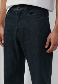 Donkerdenim jeans met een rechte snit, voorzien van een knopenfly, riemlussen en voorkoffers. De stof heeft een subtiele textuur.