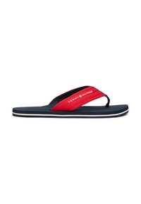 Tongs rouges et noires avec une sangle en tissu et une semelle en caoutchouc, comportant un logo blanc et une bande blanche contrastante sur le bord de la semelle.