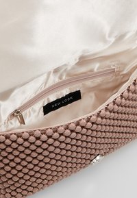 Pochette rose blush en matière texturée, avec un extérieur orné de perles, un intérieur en satin lisse et une poche zippée portant l'inscription « NEW LOOK ».