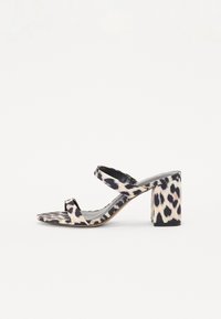 Løveprinthælende sandal med to remmer. Lavet af syntetisk materiale, har en tekstureret overflade, grå indersål og firkantet hæl.