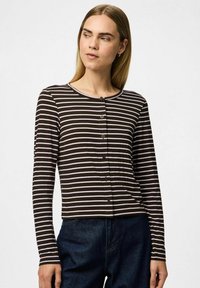 Långärmad topp med horisontella bruna och vita ränder, rund halsringning och knappstängning framtill. Mjuk, slät tyg.