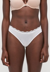 Vita bikinitrosor i slätt tyg med en detaljerad spetsmidja. Designen har minimalistiska linjer och en figurnära passform.