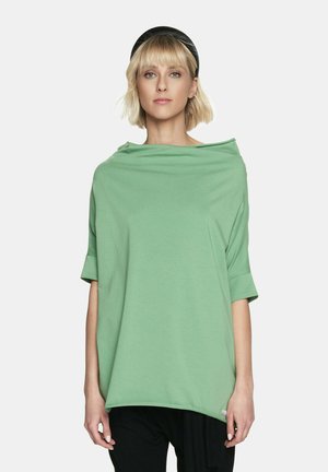Luźna, zielona, oversize'owa bluzka wykonana z miękkiego materiału, z szerokim kołnierzem i krótkimi rękawami, z subtelnym akcentem na końcu.