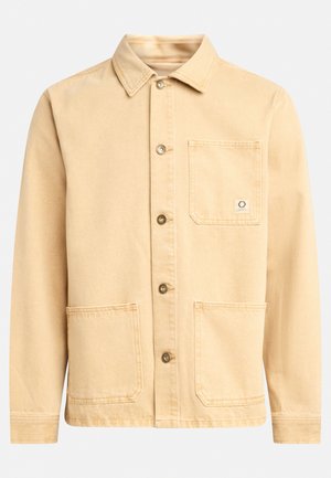 Beige cotton jacket with a collar, front button closure, two large pockets, and a small logo tag on the chest pocket. Smooth texture.