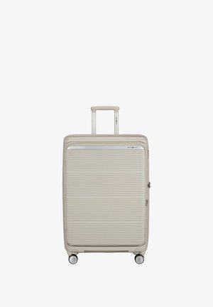 Beige hard-shell suitcase with horizontal ridges, adjustable handle extended, four spinner wheels, and Samsonite logo near top edge.