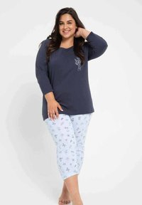 Granatowa bluzka z długim rękawem, dekoltem w serek i nadrukiem liści. Jasnoniebieskie spodnie z kwiatowymi wzorami. Miękki, wygodny materiał o luźnym kroju.