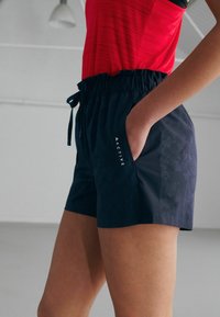I pantaloni corti da attivo blu navy presentano una cintura elasticizzata con cordino, tasche laterali e un motivo delicato. Logo 'ACTIVE' stampato sul davanti.