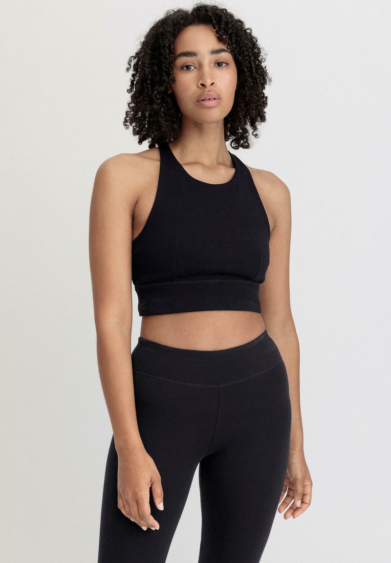 Black sports bra with a high neckline and a fitted design, showcasing a soft texture and cropped length, paired with matching high-waisted leggings.