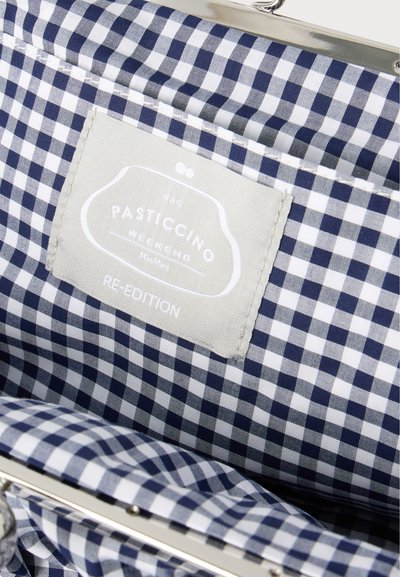 Εσωτερική επένδυση τσάντας με ύφασμα σε μπλε ναυτικό και λευκό καρό, με μια μπεζ ετικέτα που αναγράφει "Pasticcino Weekend Re-Edition".