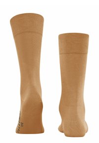Chaussettes beiges avec un bandeau supérieur texturé, un corps lisse et un logo subtil près des orteils. Fabriquées dans un matériau doux et extensible.