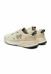 Sneaker EA7 Emporio Armani beige e bianche con dettagli in mesh e suede, loghi neri sui lati, linguette nere sul tallone e suole spesse a righe.