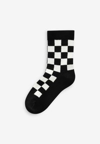 Schwarz-weiße kariertes Socken mit einem gerippten Bund, die ein Blockmuster aufweisen. Hergestellt aus einem weichen, strukturierten Material. Knöchellanges Design.