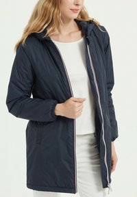 Veste bleu marine à fermeture éclair sur le devant, avec capuche, poignets élastiques et poches latérales. Fabriquée en matériau léger avec une texture lisse.