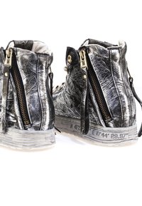 Metalen zilveren enkellaarsjes met dubbele zijritsen, gestructureerd leer en een witte rubberen zool met geprinte geografische coördinaten.