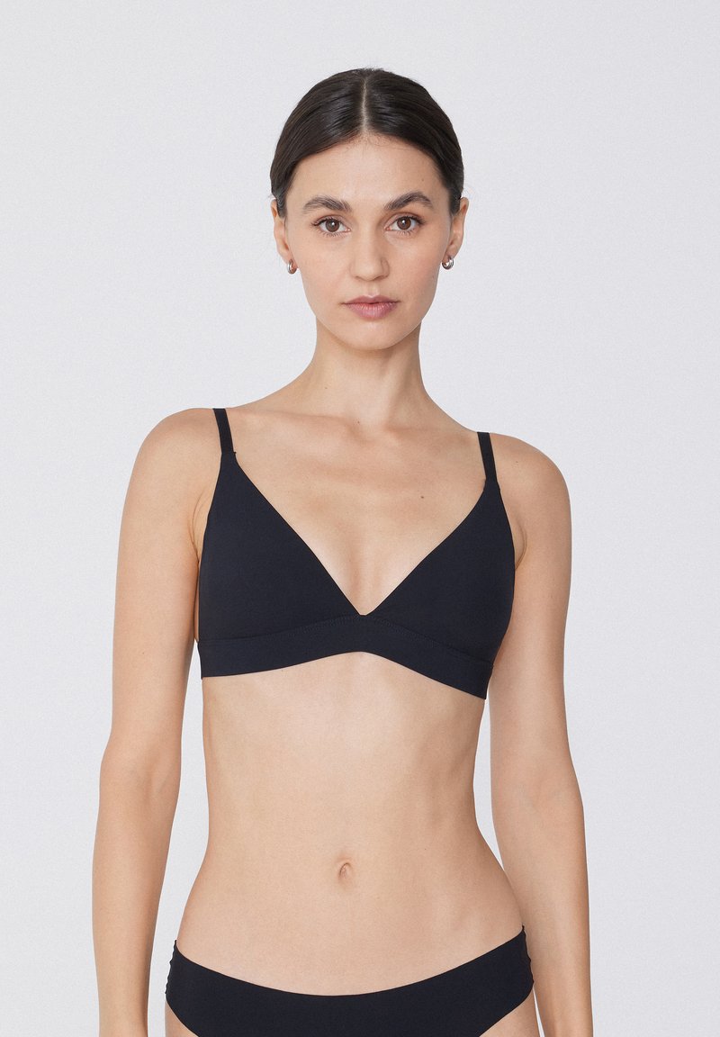 Bralette noir en triangle avec des bretelles fines et ajustables, au design sans coutures. Tissu doux avec une texture lisse, détails matériels minimaux.