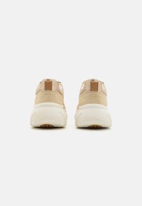 Sneaker beige con tomaia in suede, collo imbottito e suola in gomma bianca chunky; presenta un piccolo accento marrone al tallone.