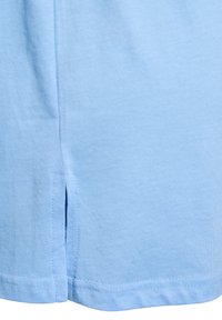 Tela de algodón azul claro, con un dobladillo recto y aberturas laterales. Textura suave y costuras limpias a lo largo de los bordes.
