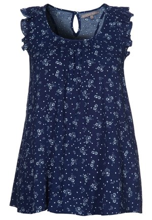 Mørkeblå bluse med korte ærmer med hvidt blomster- og polkaprikket mønster, flæseærmer, rund halsudskæring og knaplukning med nøglehul bagpå.