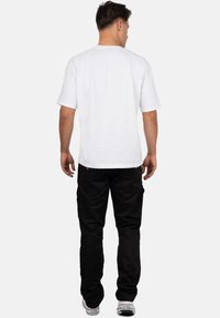 T-shirt bianca a maniche corte abbinata a pantaloni cargo neri. La t-shirt presenta un collo a giro e i pantaloni hanno tasche laterali e una vestibilità comoda.