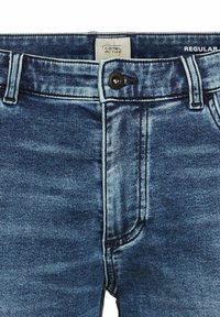 Blaue Jeans aus Denim mit mittelhoher Taille, klassischem Fünf-Taschen-Design und einer leicht verblassten Textur mit kontrastierenden Nähten und einem schwarzen Knopf.