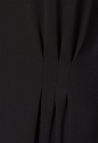 Tecido preto com uma textura suave, apresentando pregas verticais que criam detalhes subtis ao longo do design.