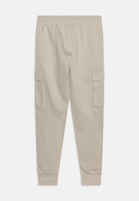 Lys beige cargo bukser med elastisk talje, to sidelommer og ribbestrikkede manchetter. Blødt stof med en glat tekstur.