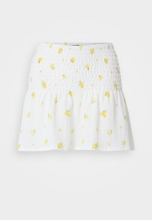 Gonna bianca con texture arricciata e motivo floreale giallo. L'orlo è svasato, creando una silhouette morbida.