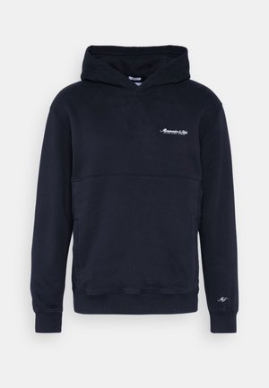 Granatowa bluza z kapturem, z kieszenią z przodu, białym logo z napisem na piersi i rękawie, z długimi rękawami i kapturem.