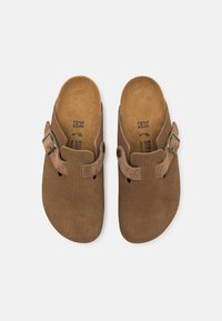 Hnedé semišové dreváky s textúrovaným povrchom, so bočným prackom a výrezmi na ventiláciu. Interiér má korokovú stielku.