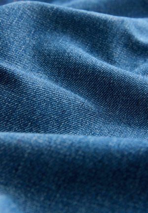 Denimstof in een diepe blauwe tint, met een gestructureerd oppervlak met zichtbare weefsels en zachte rimpelingen, wat duidt op zachtheid en flexibiliteit.