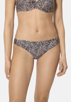 Mujer vistiendo un bikini de patrones abstractos a juego en negro y beige, posando contra un fondo claro y liso.