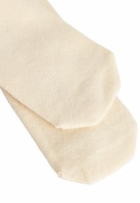 Beige bomuldsstrømper med en glat tekstur, der har en rund tå og et fladt strikmønster. To par stablet sammen.