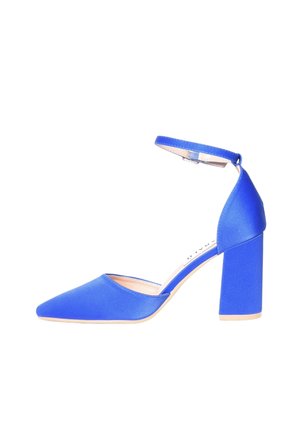 Scarpa di raso blu con tacco alto, punta appuntita e cinturino alla caviglia, tacco a blocco e suola beige su sfondo bianco.