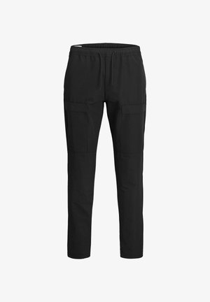 Giacca leggera verde con due tasche frontali, indossata sopra una maglietta grigia chiara. Pantaloni cargo neri con più tasche e sneakers bianche.